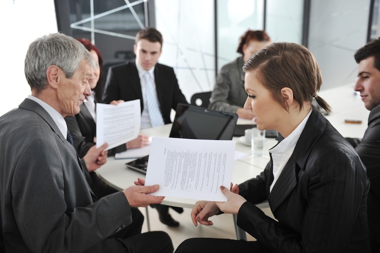 Colleagues passing papers across a table during a meeting
