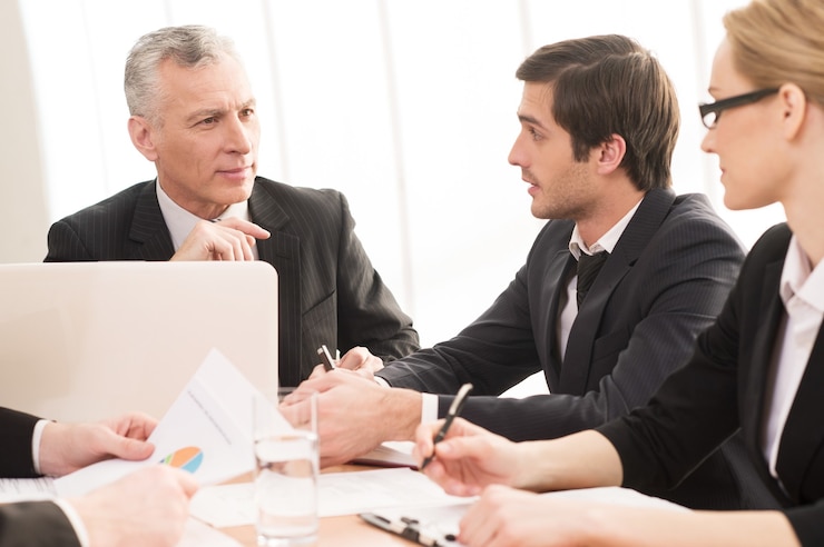 An adviser and two clients reading through documents at a table